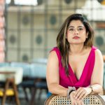 Elegant portrait of a woman in a vibrant top, set in a café in Bengaluru, exuding confidence and style.
